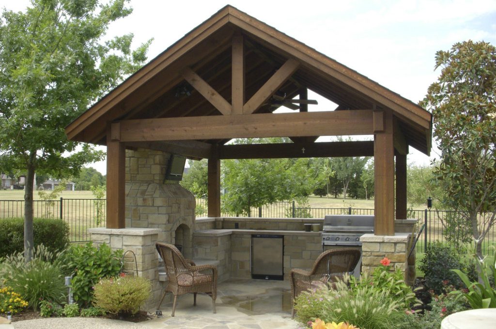 A covered outdoor grill area with chairs and tables.