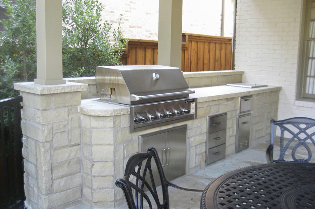 A grill sitting on top of a stone wall.