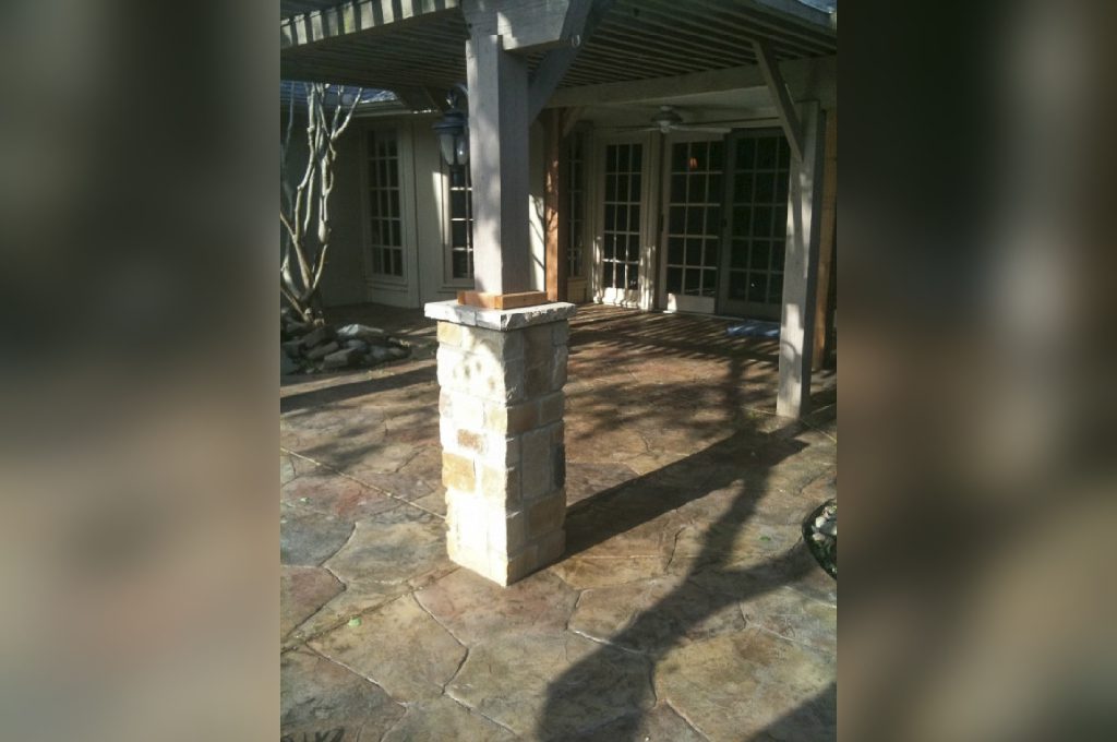 A patio with a stone pillar and a gazebo.