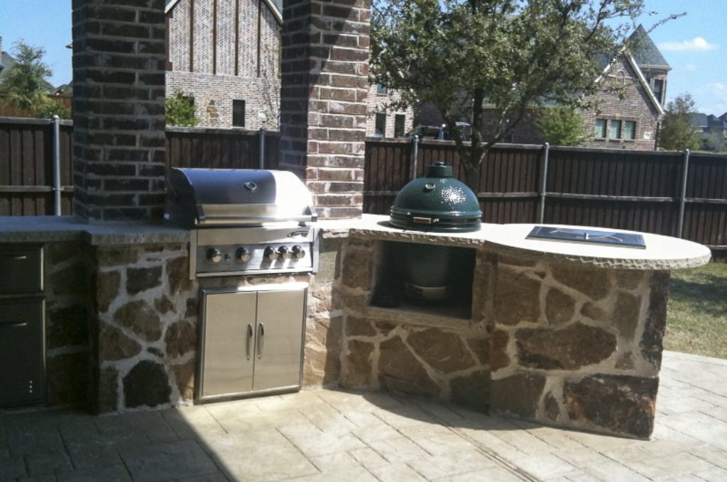 A grill and an outdoor oven in the middle of a patio.