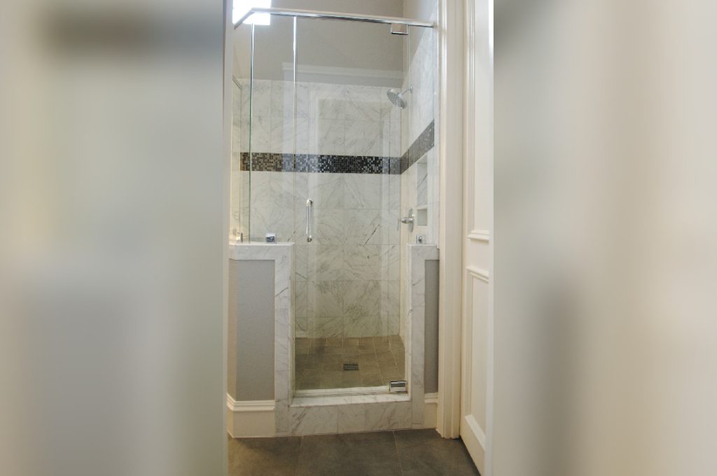 A bathroom with a walk in shower and wooden floors.
