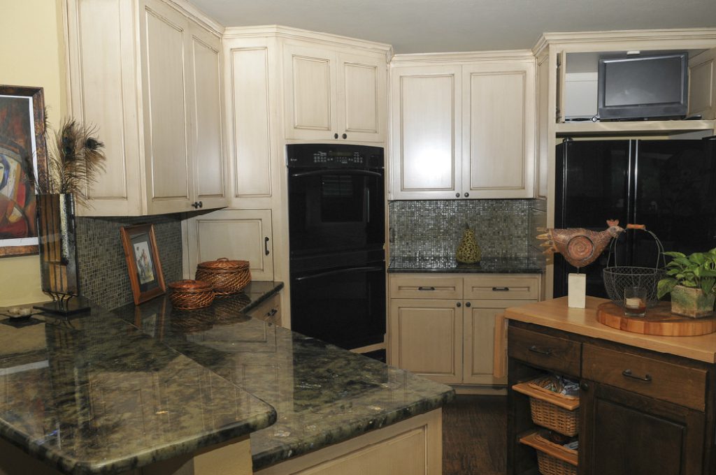 A kitchen with white cabinets and black appliances.