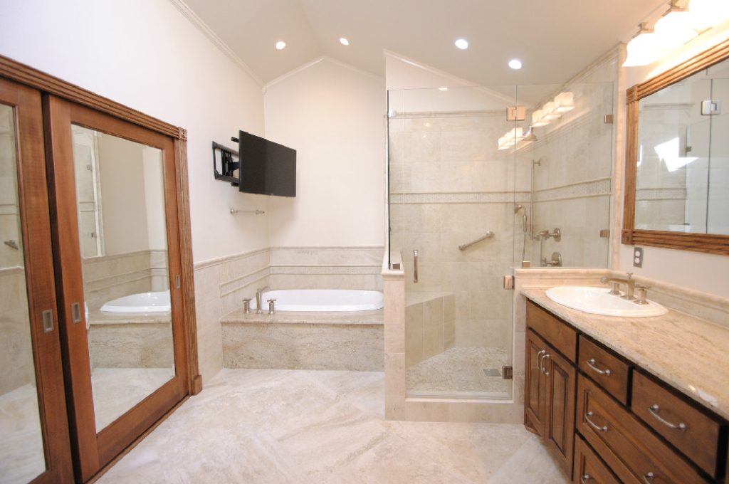 A bathroom with a large mirror and a television.
