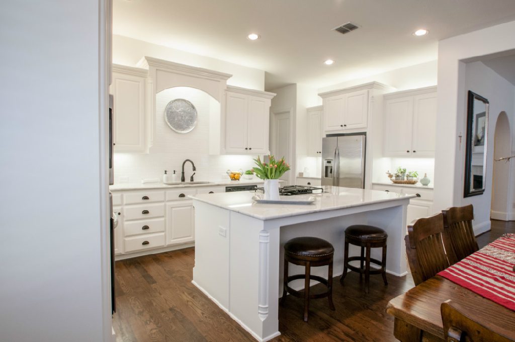 A kitchen with white cabinets and wooden floors
