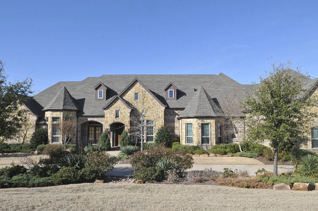 A large brick house with a stone front and a blue sky.