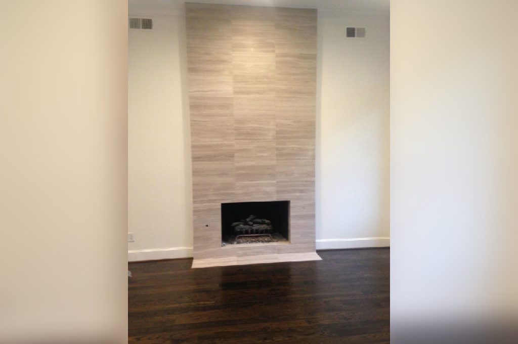 A fireplace in the corner of a room with wood floors.