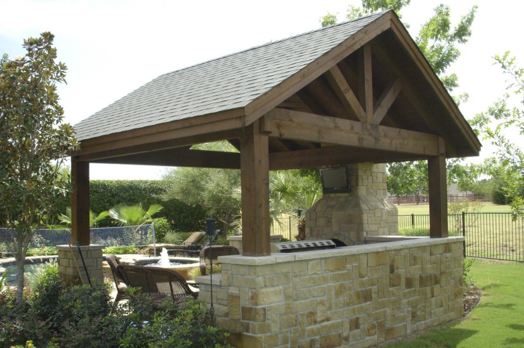 A covered outdoor grill area with tables and chairs.