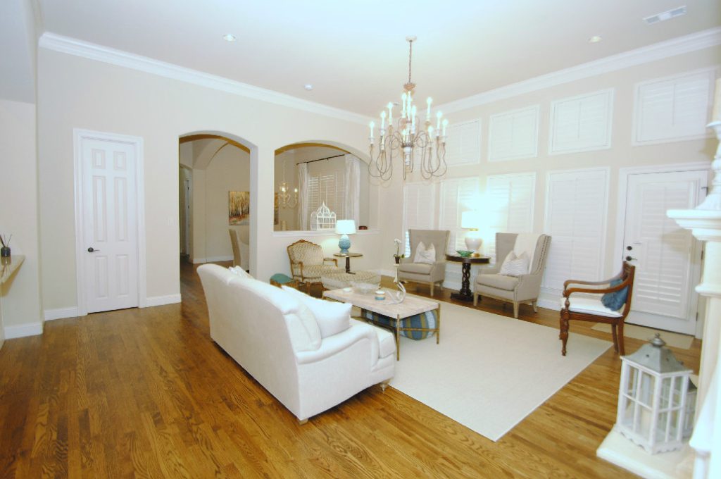 A living room with white furniture and wood floors.