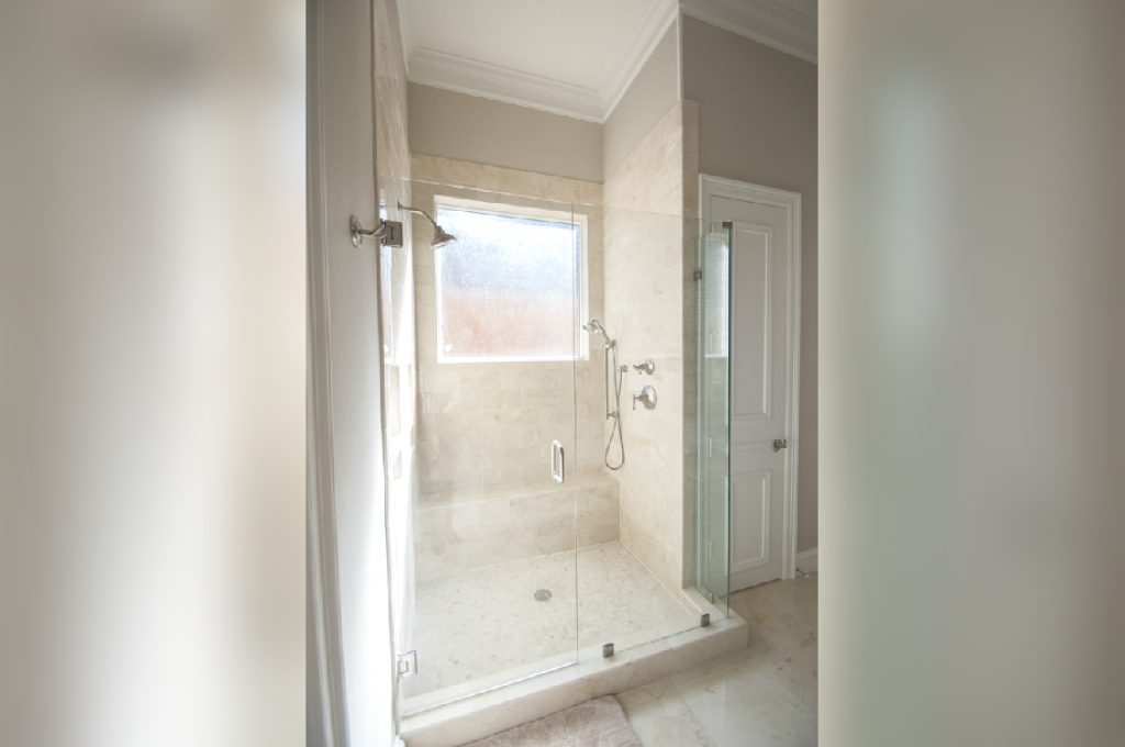 A bathroom with a large shower and tiled floors.