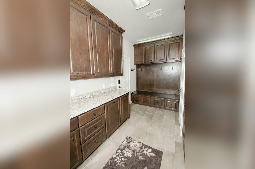 A kitchen with brown cabinets and white tile floors.