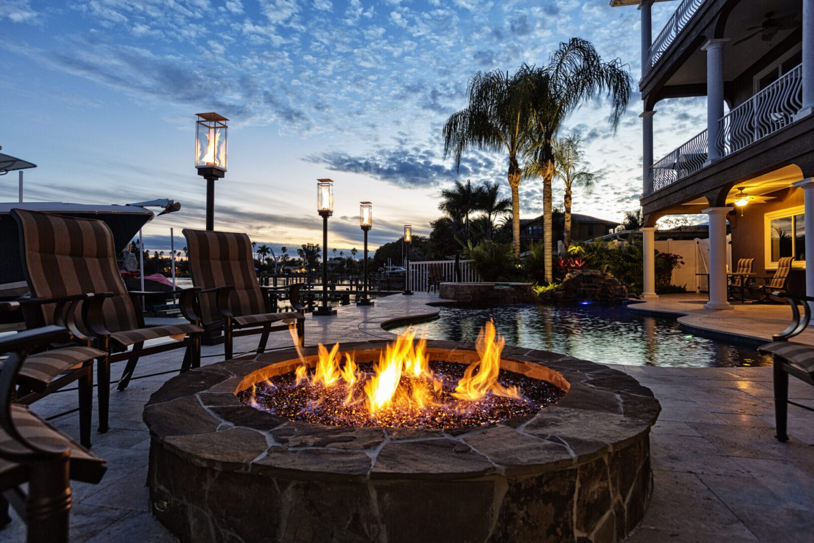 Fire pit by pool at sunset scene.