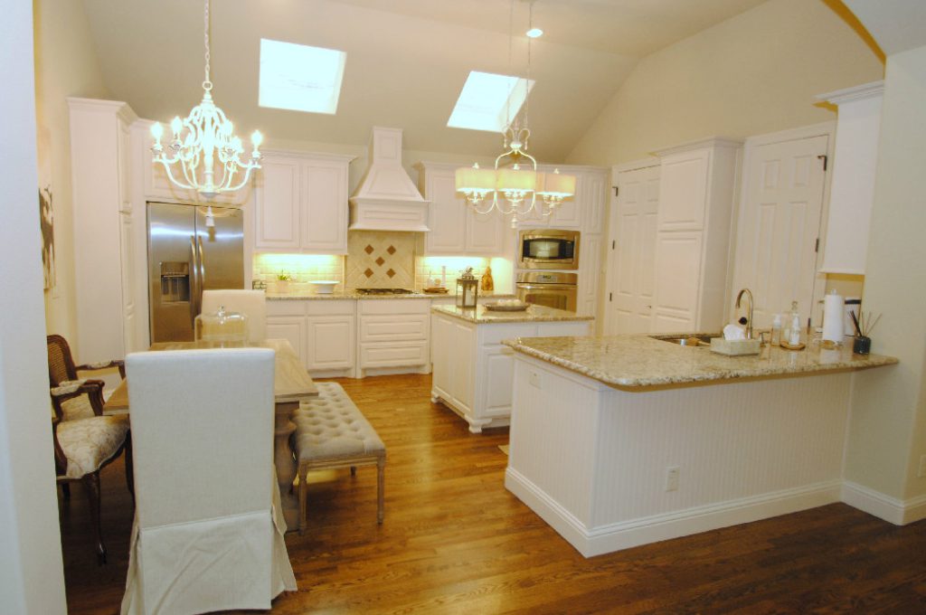 A kitchen with white cabinets and wooden floors