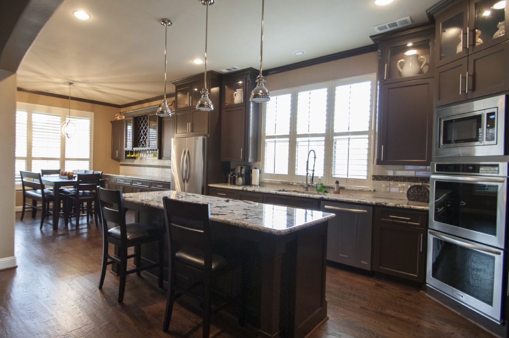 A kitchen with dark cabinets and wood floors.