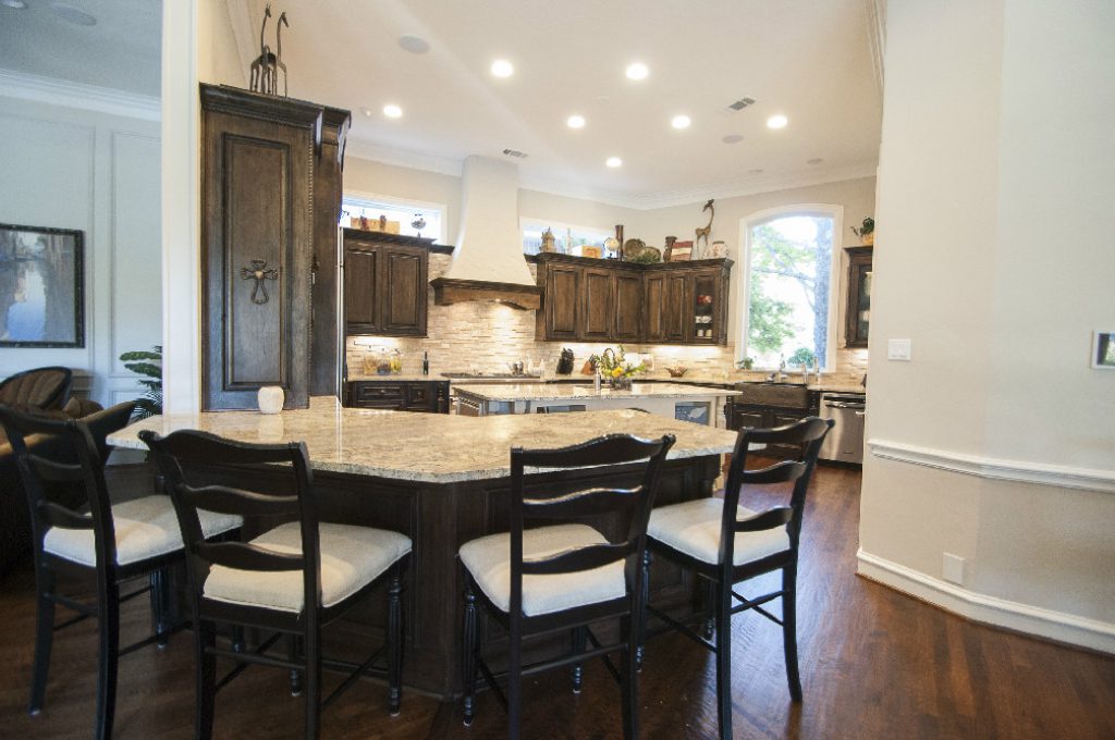 A kitchen with a large island and wooden chairs.