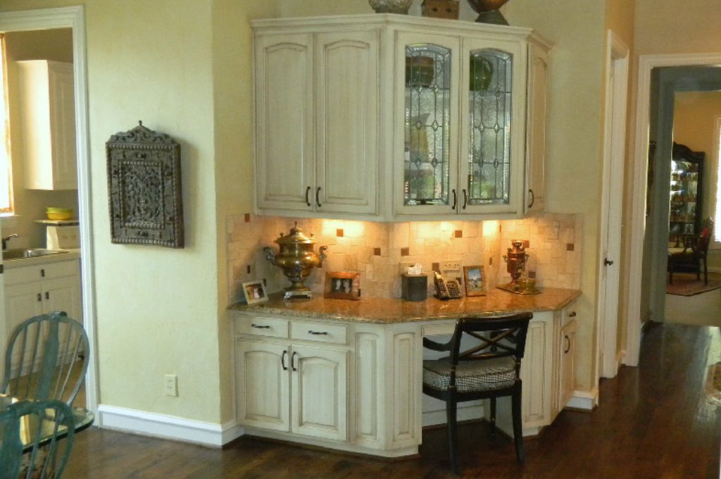 A corner desk with a chair and cabinets in the kitchen.
