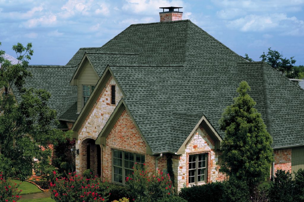 A house with green shingles and a brick roof.