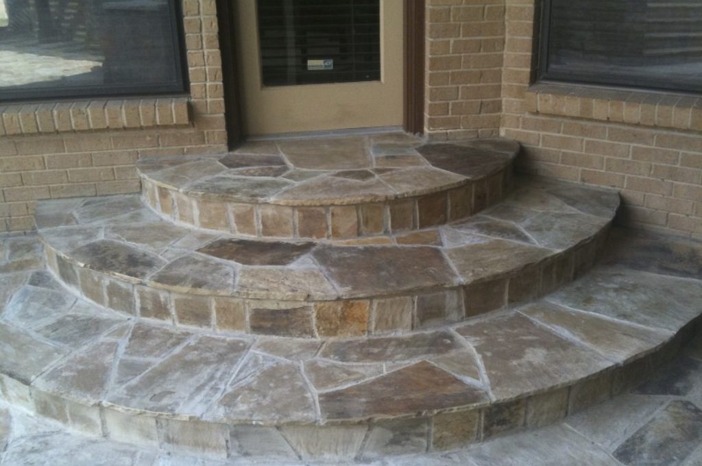 A stone patio with steps leading to the front door.