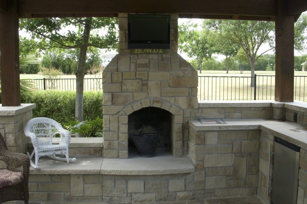 A stone fireplace with television above it