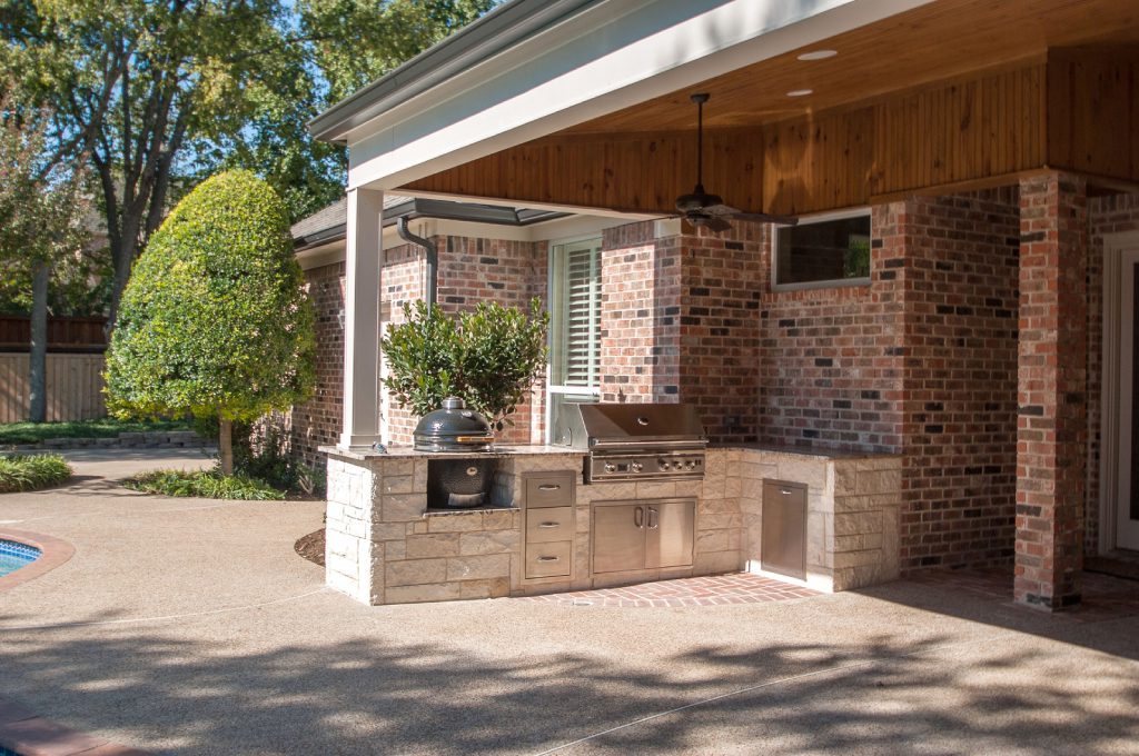 A grill and an outdoor kitchen in the middle of a patio.