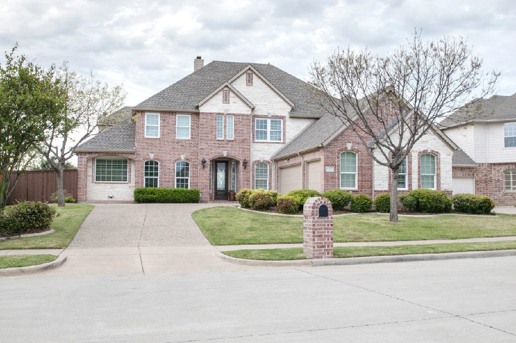 A large brick house with a driveway and trees.