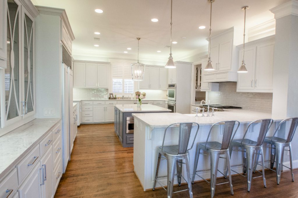 A kitchen with white cabinets and wooden floors