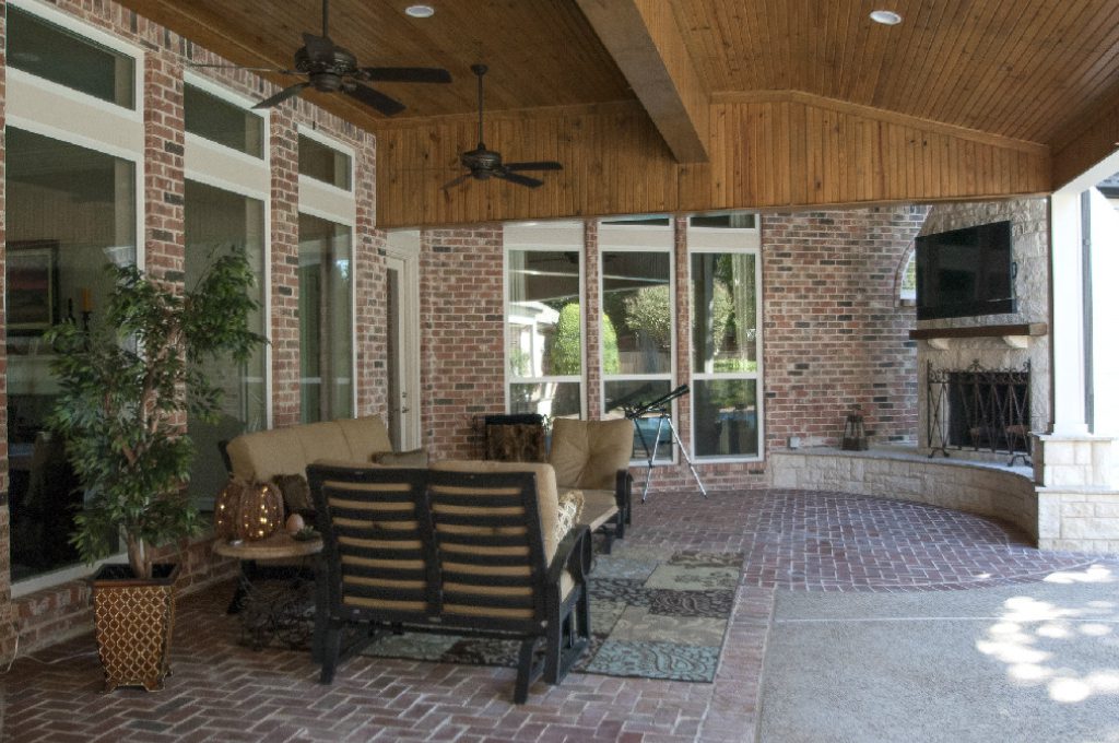 A patio with furniture and a fireplace in the middle of it.
