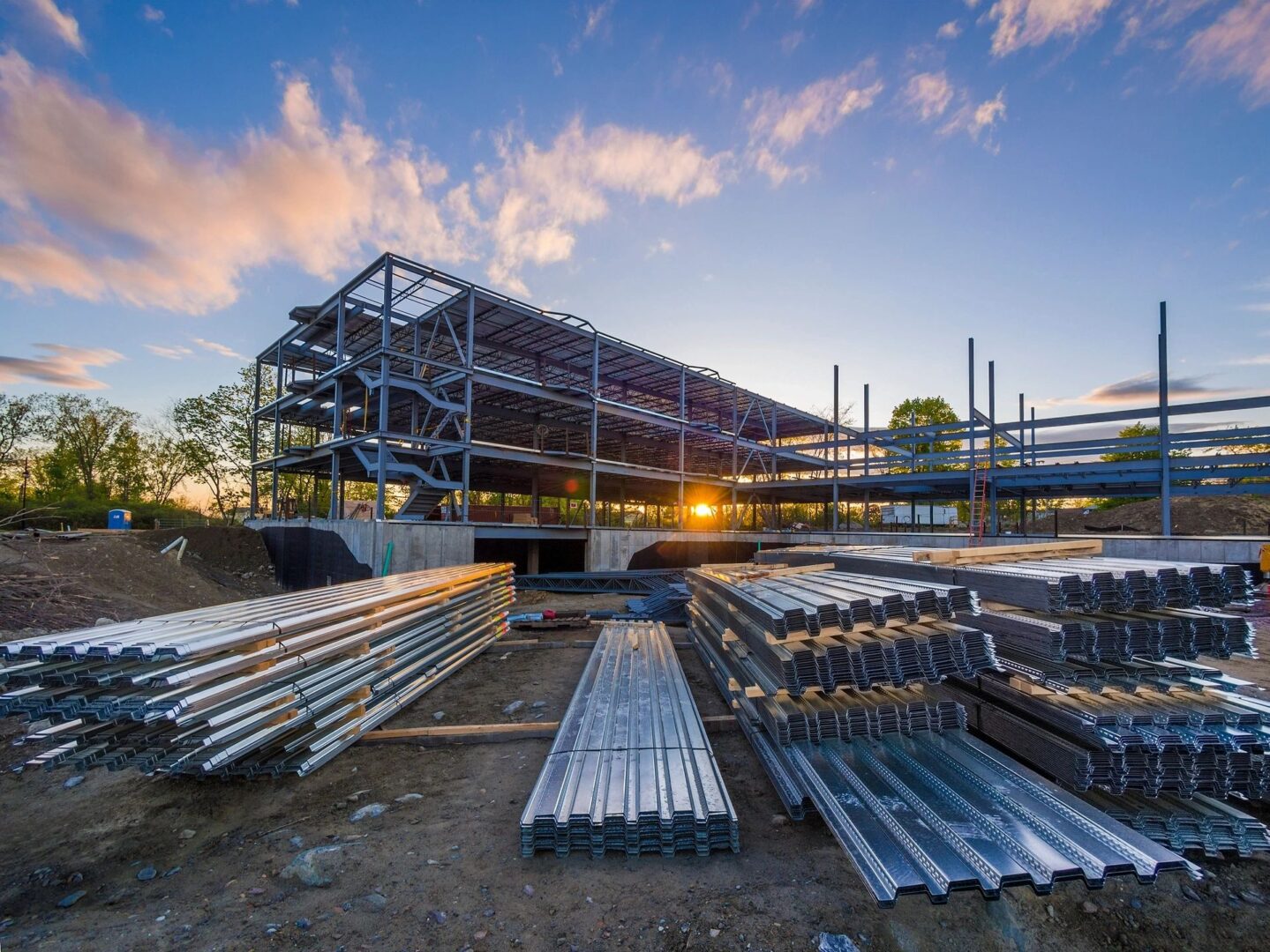 Construction site with steel beams, sunset view.